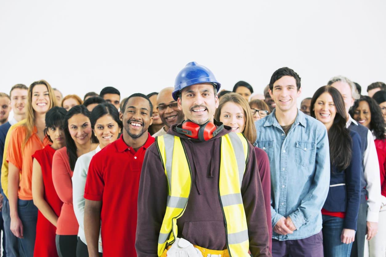 Group of workers from all backgrounds standing together with the lead person being a construction worker